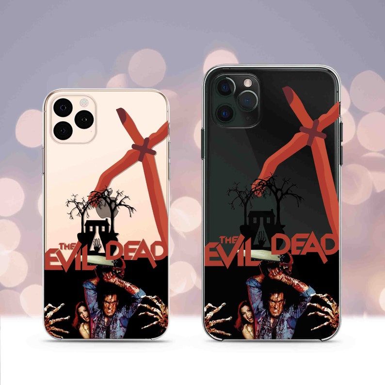 Puede incluir: Dos fundas transparentes para tel&eacute;fono con una imagen en blanco y negro de un personaje de la pel&iacute;cula "The Evil Dead" sosteniendo una motosierra. La imagen se superpone a un gr&aacute;fico rojo y naranja de una mano que se extiende desde la parte superior de la funda. El texto "The Evil Dead" est&aacute; impreso en blanco en la funda.
