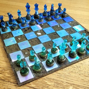 May include: A blue and brown resin chess set with a glitter finish. The chessboard is made of resin and has a blue and brown design. The chess pieces are made of glass and have a blue and white design.