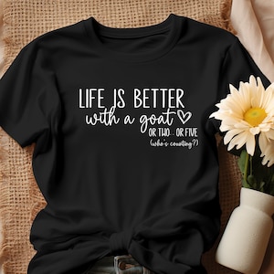 May include: Black t-shirt with white text that reads "LIFE IS BETTER with a goat OR TWO.. OR FIVE (who's counting?)".