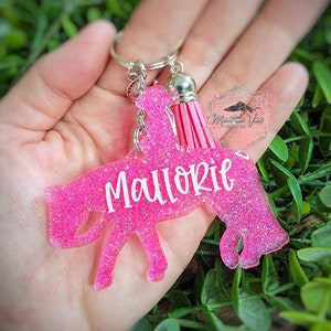 May include: Pink glitter horse keychain with a pink tassel and the name "Mallorie" written in white.