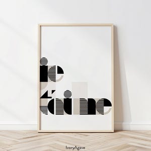 May include: A black and white geometric abstract art print with the word "time" in the design. The print is framed in a light wood frame and is hanging on a white wall.