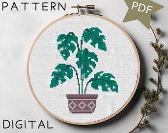 May include: A cross stitch pattern featuring a potted plant with large green leaves. The pattern is displayed in a wooden embroidery hoop. The text "CROSS STITCH PATTERN" and "PDF" are visible in the image.