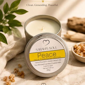 May include: A silver-colored candle tin with a white label that reads "Peace" and lists ingredients. The candle is surrounded by leaves and small pieces of amber-colored resin. The text "Find Your Moment" is at the top.