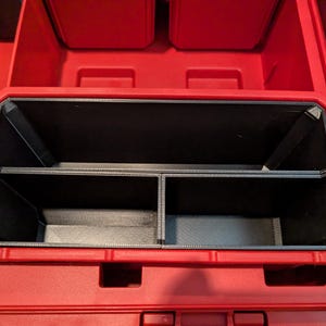 May include: A red plastic tool box with a black interior organizer. The organizer has multiple compartments for storing tools and accessories. The tool box is designed for durability and organization.