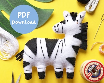 May include: A black and white felt zebra toy with a smiling face. The zebra is on a yellow background with sewing supplies, including thread, scissors, and a spool of thread.
