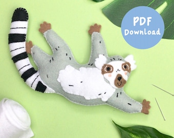 May include: A felt lemur sewing pattern with a PDF download button. The lemur is gray with white markings and a black and white striped tail. The pattern includes instructions for sewing the lemur.