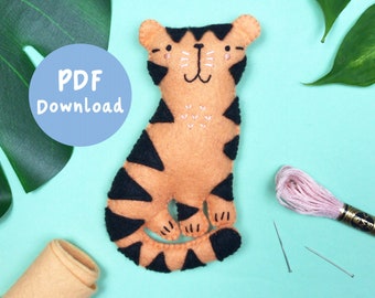 May include: A felt tiger sewing pattern with a PDF download button. The tiger is orange with black stripes and has a friendly face. The pattern includes instructions for sewing the tiger and a list of materials needed.