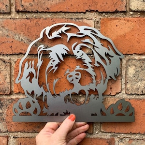 May include: A metal silhouette of a dog's head with paw prints at the bottom. The silhouette is a dark silver colour.