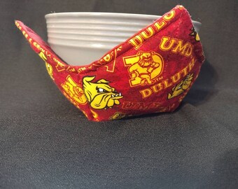 May include: Red fabric bowl cozy with a yellow bulldog and "UMD DULUTH" text.