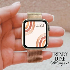 May include: A gold Apple Watch with a brown and orange abstract design watch face. The time is 2:23.