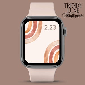 May include: A pink Apple Watch with a white watch band displays a digital clock face with the time 2:23. The watch face has a background of abstract watercolor arches in shades of orange, brown, and red.