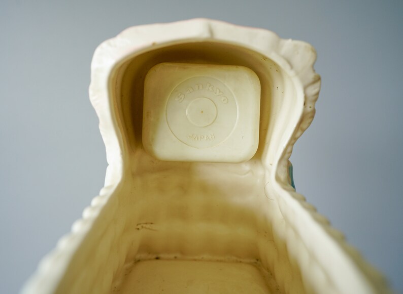 May include: A white ceramic baby crib with a removable white plastic insert that reads "Star-Kist Japan".