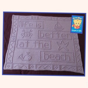May include: A lavender crocheted baby blanket with the text "Life is better at the beach" in raised stitches.
