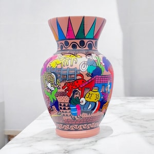 Könnte beinhalten: Eine handbemalte Keramikvase mit breitem Boden und ausgestelltem Rand. Die Vase hat ein farbenfrohes Design mit Figuren, Tieren und geometrischen Mustern in Rot-, Blau-, Gelb- und Grüntönen. Der Rand ist mit einem Regenbogenmuster verziert.