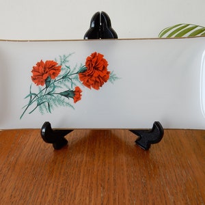 Op de afbeelding: Een wit rechthoekig dienblad met een gouden rand en een bloemmotief met rode anjers en groene bladeren.