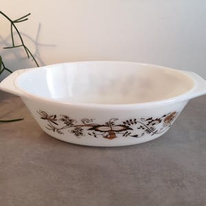 Op de afbeelding: Witte ovale ovenschaal met een bruin bloemenpatroon. De schaal heeft twee handvatten aan de zijkanten.