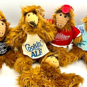 May include: Five brown furry plush toys of the alien character ALF from the 1980s television show. Each toy is wearing a different outfit. One is wearing a black shirt with the words "Born to Rock", another is wearing a white apron with the words "Cookin' with ALF", another is wearing a red shirt with the word "Melrose", another is wearing a blue Hawaiian shirt, and the last one is wearing a chef's hat.