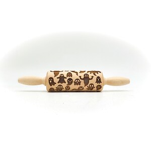 Peut inclure: Un rouleau &agrave; p&acirc;tisserie en bois avec un motif de fant&ocirc;mes sculpt&eacute;s dans la surface. Le rouleau &agrave; p&acirc;tisserie est brun clair et a une finition en bois naturel.