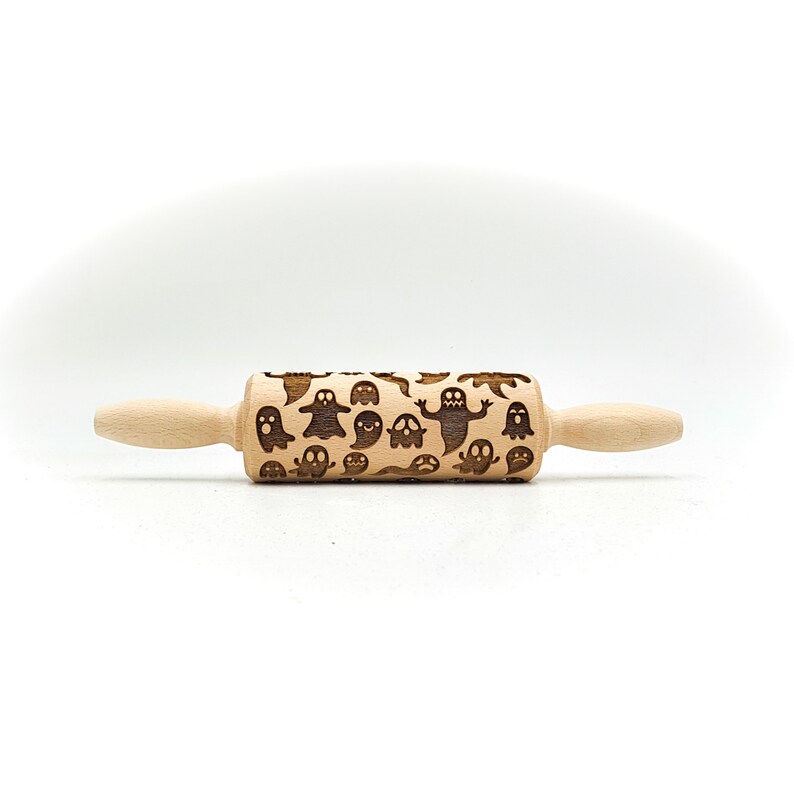 Peut inclure: Un rouleau &agrave; p&acirc;tisserie en bois avec un motif de fant&ocirc;mes sculpt&eacute;s dans la surface. Le rouleau &agrave; p&acirc;tisserie est brun clair et a une finition en bois naturel.