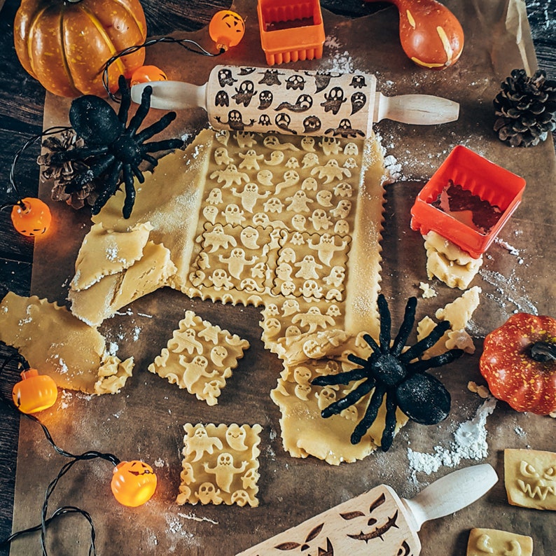 Peut inclure: Un gros plan sur un ensemble d'emporte-pi&egrave;ces sur le th&egrave;me d'Halloween avec un rouleau &agrave; p&acirc;tisserie et diverses formes de p&acirc;te &agrave; biscuits. Les emporte-pi&egrave;ces sont en forme de fant&ocirc;mes et le rouleau &agrave; p&acirc;tisserie a un motif de fant&ocirc;me. La p&acirc;te &agrave; biscuits est d&eacute;coup&eacute;e en diverses formes, notamment des fant&ocirc;mes, des citrouilles et des chauves-souris.