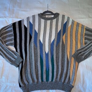 May include: A gray striped sweater with a geometric pattern in black, white, blue, green, and yellow.