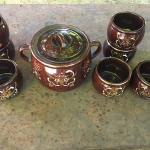 May include: A set of brown ceramic bowls and a covered casserole dish with a floral design. The bowls are stacked in pairs and the casserole dish has a lid.