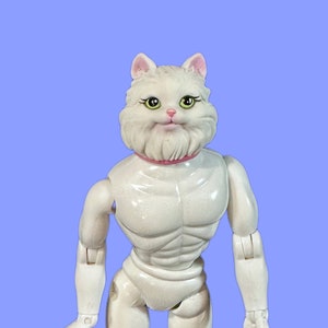 May include: White plastic action figure of a cat with a human body. The cat has a white fluffy head with green eyes and a pink collar. The figure has a muscular torso and is standing with its arms at its sides.