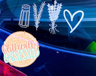 May include: A blue car with a white sticker that says "glitterally obsessed" on a leopard print background. There are other white stickers on the car, including a salt shaker, a sprig of rosemary, a bunch of lavender, and a heart.