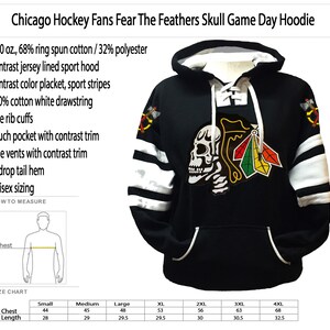 Może przedstawiać: Czarna bluza z kapturem w białe paski z logo czaszki i pi&oacute;r. Bluza ma sznurek, kieszeń kangurkę i boczne rozcięcia. Tekst "Chicago Hockey Fans Fear The Feathers Skull Game Day Hoodie" znajduje się u g&oacute;ry obrazu. Tabela rozmiar&oacute;w pokazuje rozmiary od S do 4XL z odpowiadającymi im wymiarami klatki piersiowej i długości w calach.