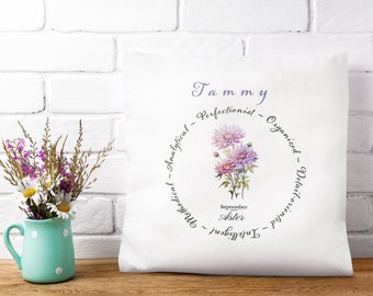 May include: White square pillow with a floral design featuring purple and pink flowers. The pillow has the name "Tammy" and the words "Perfectionist, Organized, Detailed-oriented, Intelligent, Analytical" around the flowers.