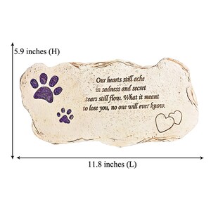 May include: A beige stone-shaped memorial plaque, 30 cm long and 15 cm high, with purple glitter paw prints and a heart design. The inscription reads: "Our hearts still ache in sadness and secret tears still flow. What it meant to lose you, no one will ever know."