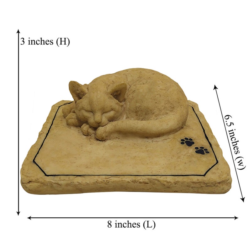 May include: A tan, sculpted sleeping cat figurine resting on a rectangular base with two black paw prints. The base features dimensions of 8 inches in length, 6.5 inches in width, and 3 inches in height, as indicated by the visible measurement labels.