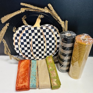 May include: A craft supply set featuring a black and white checkered pumpkin sign, a black wire wreath frame with gold tinsel, two rolls of mesh ribbon in black and gold, and four spools of ribbon in orange velvet, teal glitter, tan, and green leaf print.