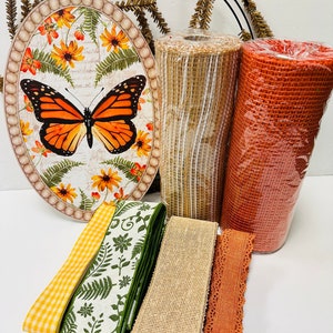May include: A set of fall-themed crafting supplies including a round wooden sign with a butterfly and floral design, two rolls of orange and tan mesh ribbon, and four rolls of ribbon in orange, tan, green, and yellow.