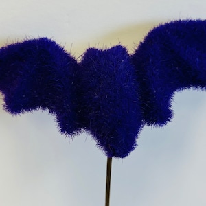 May include: A purple fuzzy bat decoration with a wire stem.