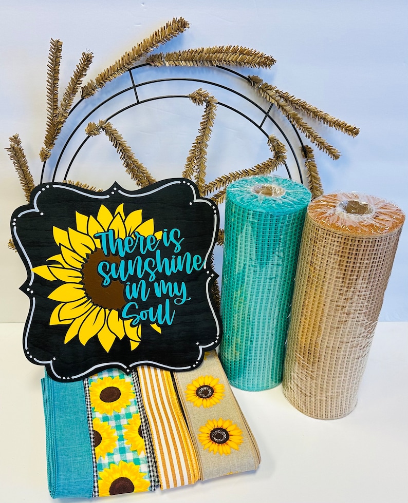 May include: A craft supply kit for making a sunflower wreath. The kit includes a metal wreath form, brown and teal mesh ribbon, sunflower patterned ribbon, and a wooden sign that reads "There is sunshine in my soul".