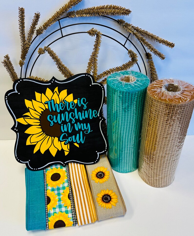 May include: A wooden sign with a sunflower and the text "There is sunshine in my soul". The sign is surrounded by teal and brown mesh ribbon, gold and white striped ribbon, and a teal and white gingham ribbon with sunflowers.