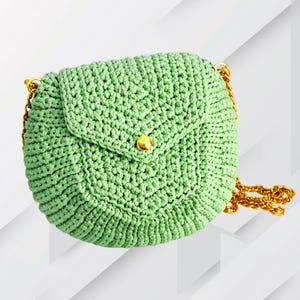 May include: A light green, crocheted purse with a flap closure and a gold-colored button. The purse has a gold chain strap. The bag is round and has a textured appearance. The background is white with gray geometric shapes.