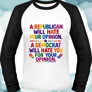 Può includere: Una maglietta bianca a maniche lunghe con maniche nere. La maglietta presenta il testo "A REPUBLICAN WILL HATE YOUR OPINION. A DEMOCRAT WILL HATE YOU FOR YOUR OPINION." in glitter arcobaleno.
