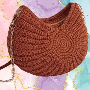 Peut inclure: Un sac à main marron crocheté avec une fermeture éclair dorée et une bandoulière en chaîne. Le sac a une forme arrondie avec un motif en spirale sur le devant. La bandoulière est de couleur argentée.