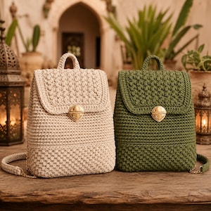 Pode incluir: Duas mochilas de crochê, uma em bege e outra em verde-oliva, com um padrão de pontos texturizados, uma alça superior, uma aba com fecho giratório de metal dourado e alças de ombro de crochê combinando com elos de corrente de metal dourado.
