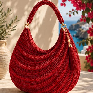 May include: A vibrant red crochet hobo bag featuring a textured, ribbed stitch pattern. The bag has a single rounded handle, gold-toned metal hardware rings, and a matching red tassel charm attached to a gold chain on the side of the bag.