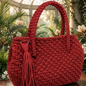 May include: A red crocheted handbag with a braided handle and a tassel. The bag has a textured stitch pattern and a rounded shape. The background features lush greenery and a glass structure.