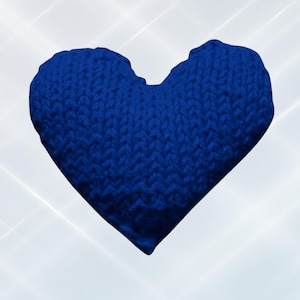 Può includere: Un cuore lavorato a maglia di colore blu intenso. La trama della maglia è ben visibile, aggiungendo profondità e dettaglio alla forma morbida e soffice. La forma del cuore è completa, con una leggera rientranza nella parte superiore.