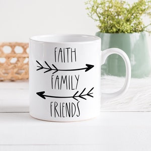 May include: White ceramic mug with black text and arrows that reads "Faith Family Friends".