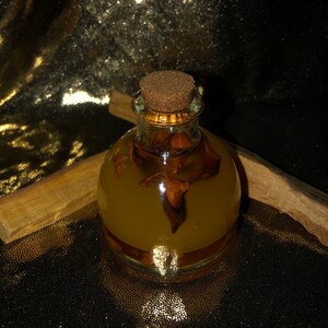 May include: A clear glass bottle with a cork stopper filled with a yellow liquid and brown pieces of dried fruit. The bottle is sitting on a black surface.
