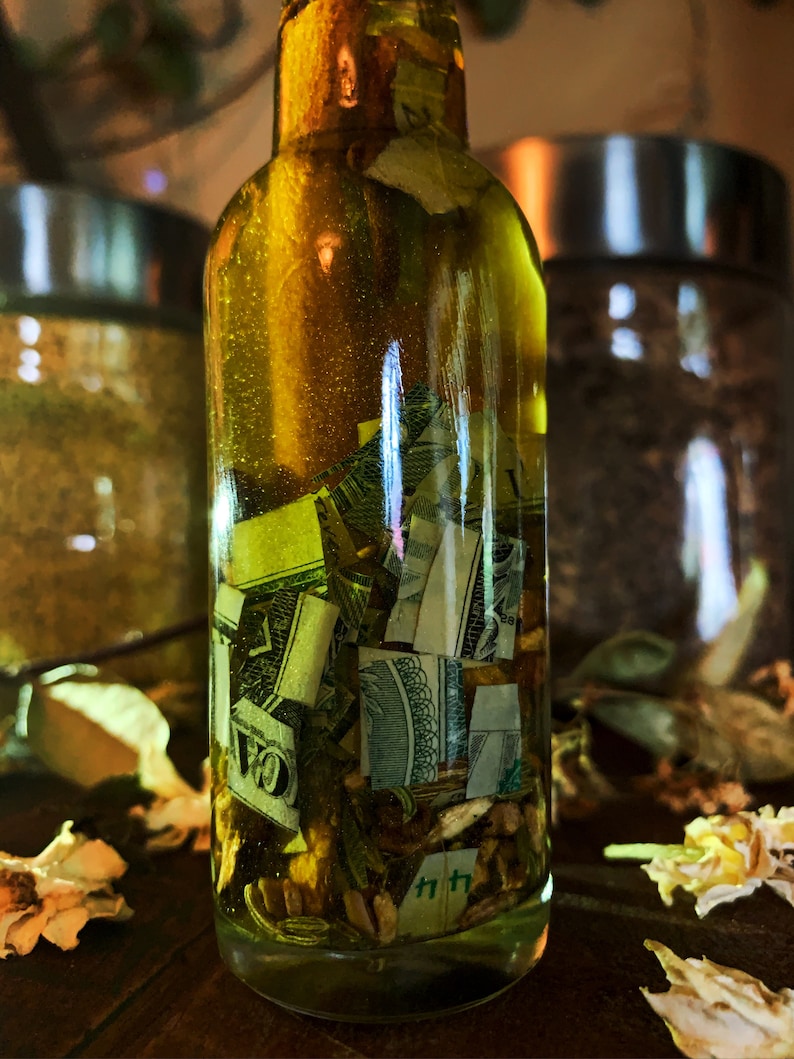 Op de afbeelding: Een doorzichtige glazen fles gevuld met een gele vloeistof en papiergeld. De fles staat op een houten oppervlak.