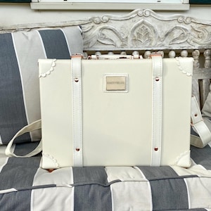 May include: A white vintage-style suitcase with gold accents and the text "Daisy Fields" on the front.