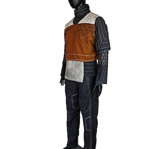 Puede incluir: Un chaleco acolchado negro y marrón con un panel blanco y pantalones negros con costuras blancas. El chaleco tiene un cuello alto y los pantalones tienen varios bolsillos.