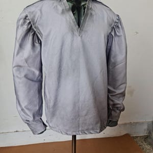 May include: A light gray long-sleeved shirt with a V-neck and a stand-up collar.